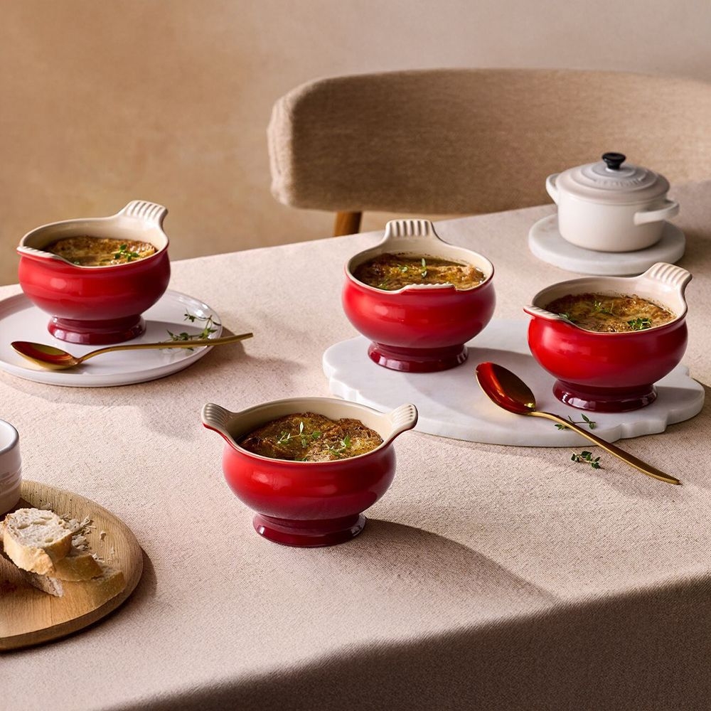 Set table with red ceramic soup bowls