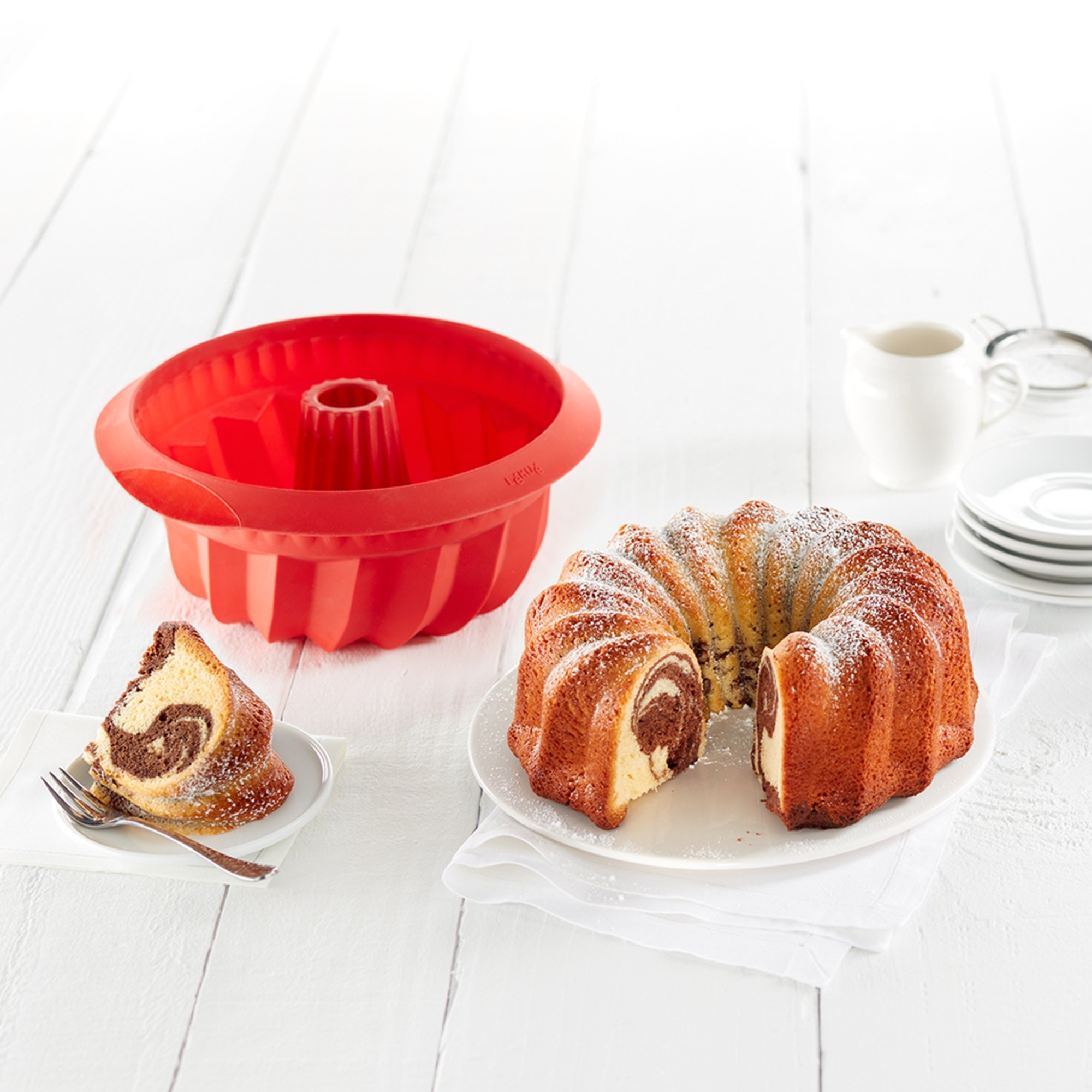 Red silicone bundt mould with baked marble cake