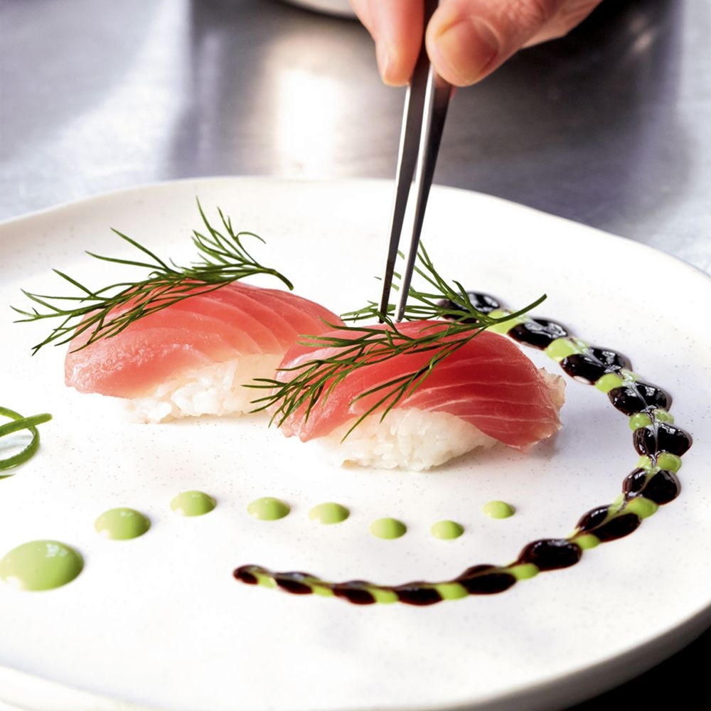 Two tuna nigiri with dill and sauce decor