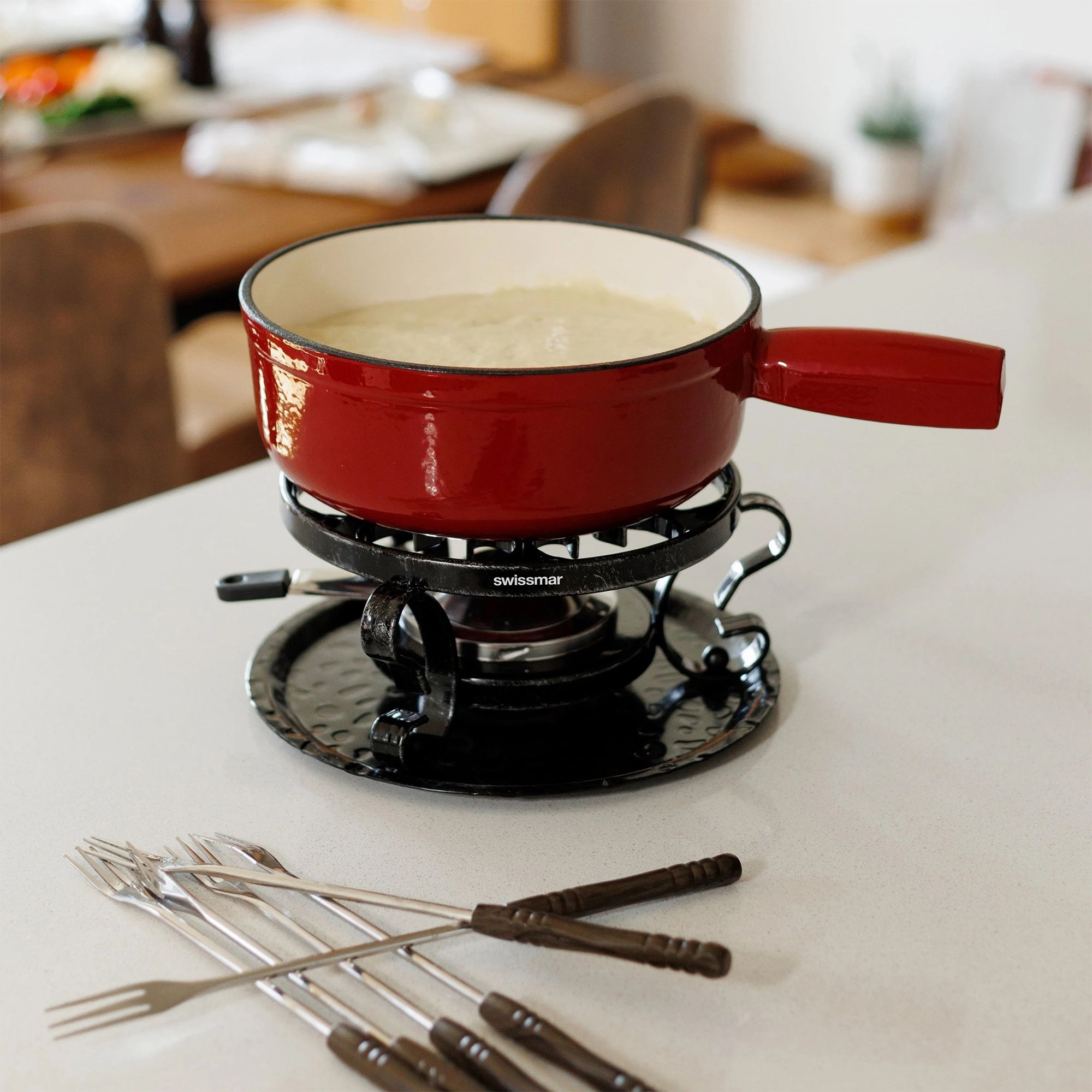 Red cheese fondue set with forks on table