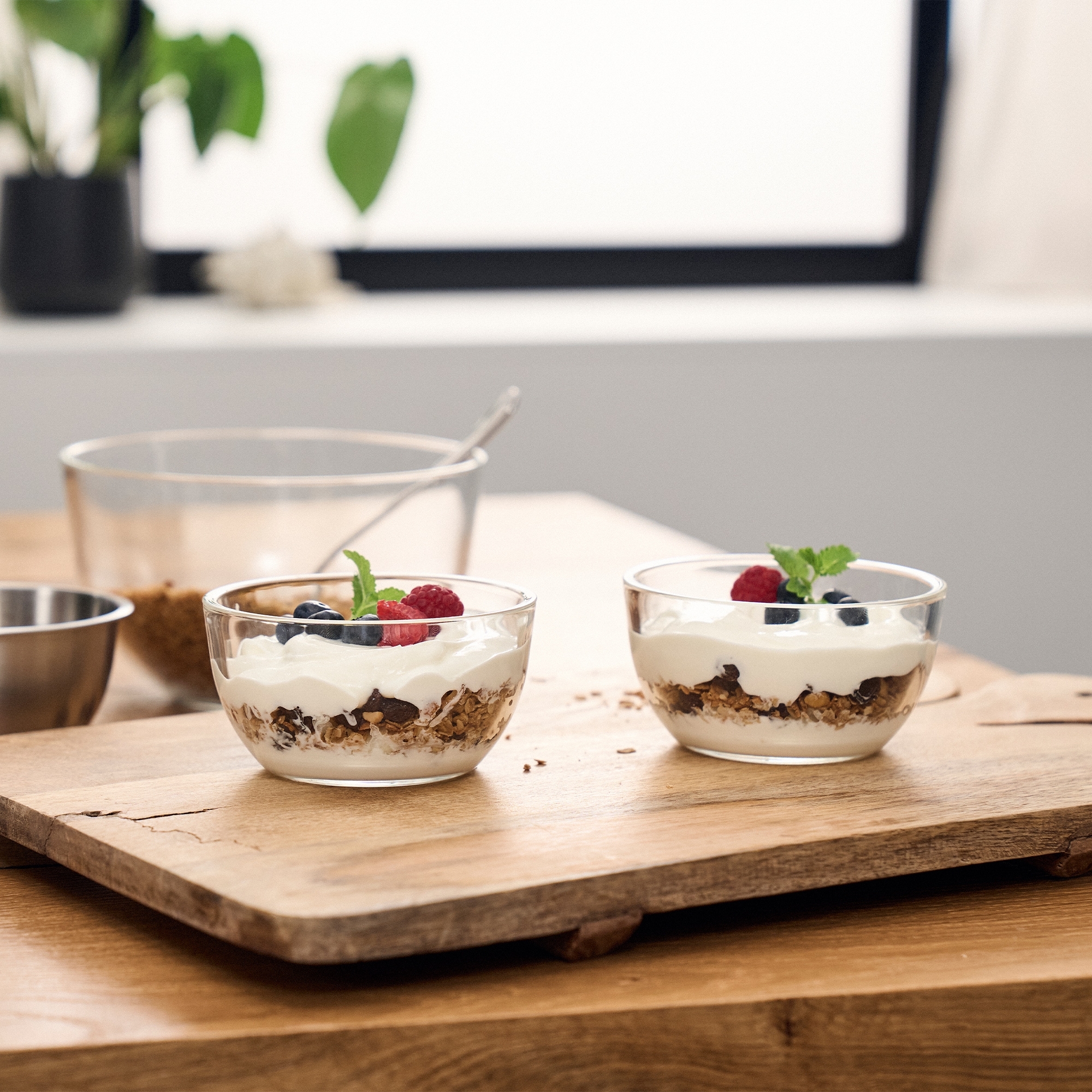 Zwei Glas-Schalen mit Joghurt, Granola und frischen Beeren a