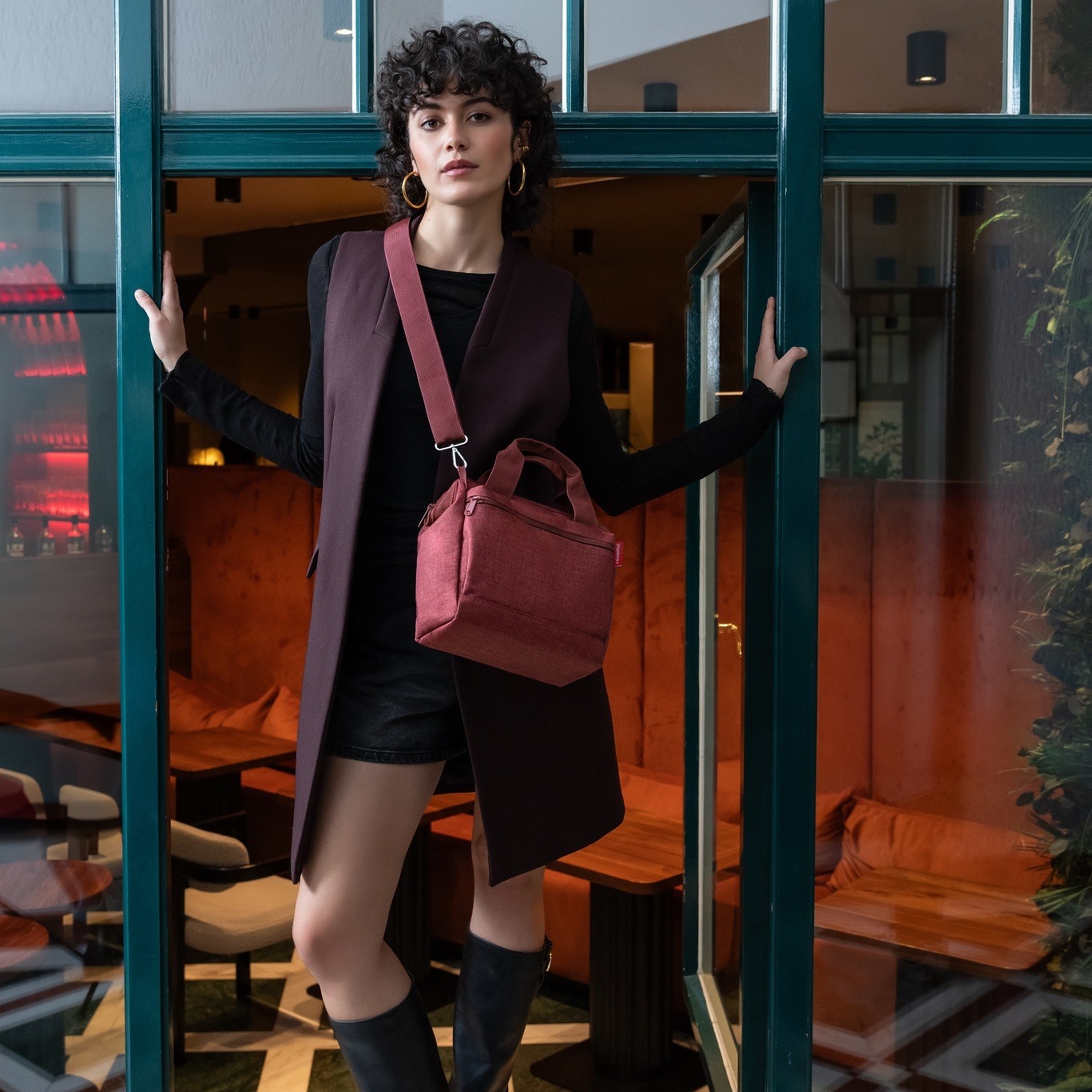 Woman with elegant burgundy shoulder bag in café