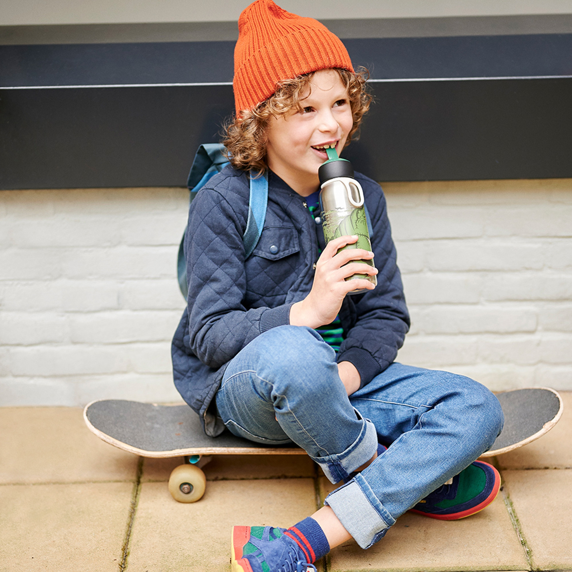 Child drinking from Mepal Campus Flip-Up turquoise bottle