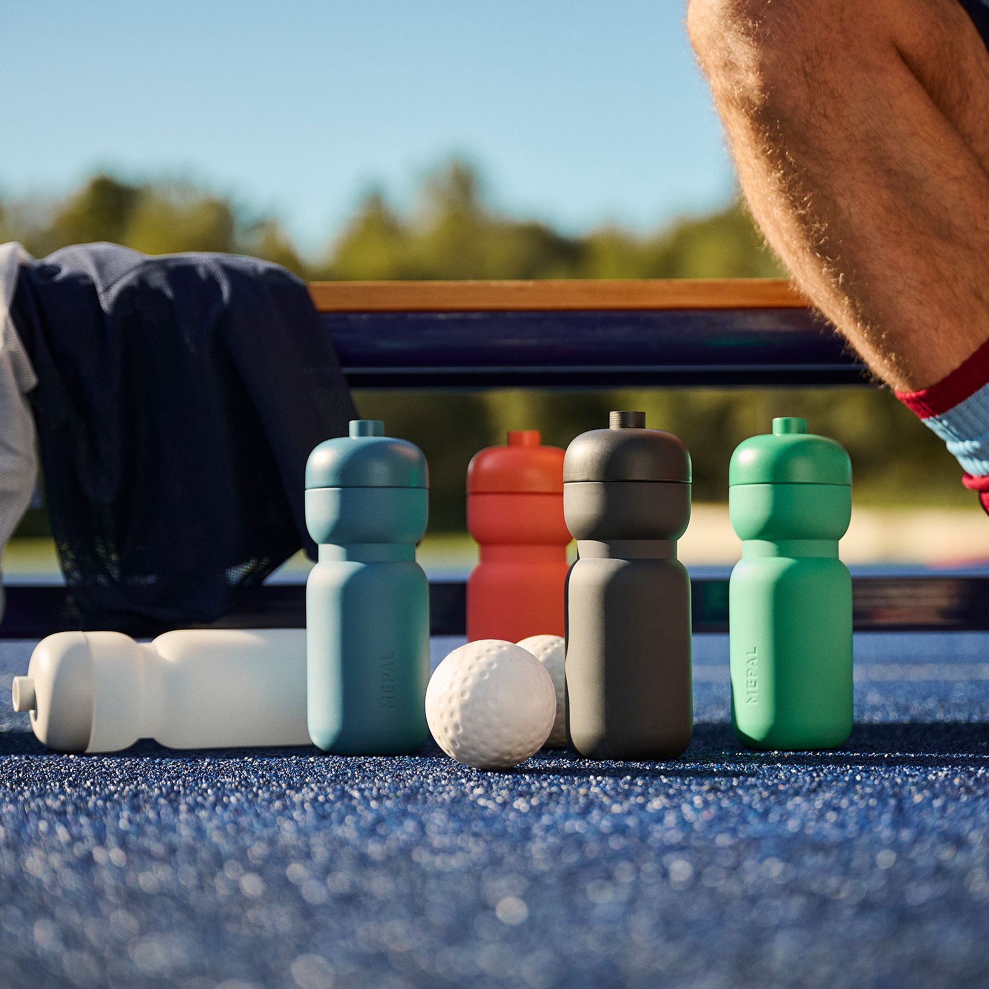 Farbige Trinkflaschen aus Kunststoff neben Sportbällen